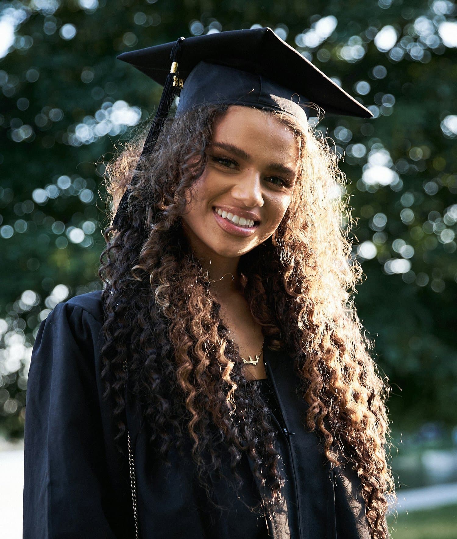 A smiling graduate wearing a graduation cap and gown, from the existing Change the Cycle website